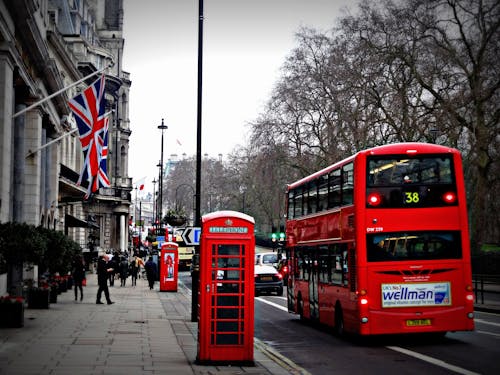 Free Classic London scene featuring a red double-decker bus and iconic phone booth on a busy city street. Stock Photo