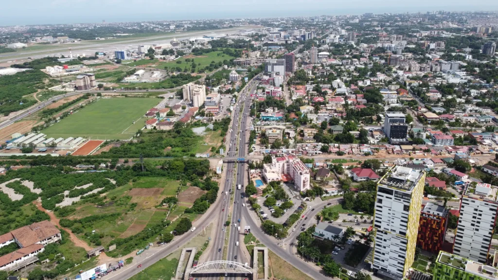 Aerial view of Airport City in Accra featuring modern skyscrapers, major roads, and Kotoka International Airport runway, highlighting corporate travel management in Ghana.