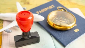 A close-up of an official visa approval stamp, passport, compass, and model airplane on a map, illustrating a Ghana work and residence permit application.