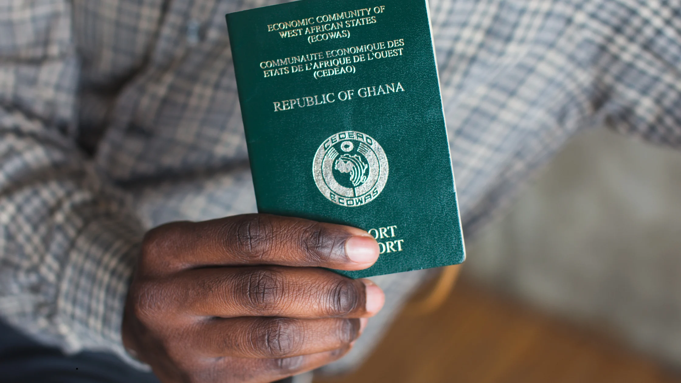 Close-up of a person holding a green ECOWAS, Republic of Ghana passport, highlighting international travel requirements and being used as a featured image for an article about visa on arrival for Ghana passport holders.