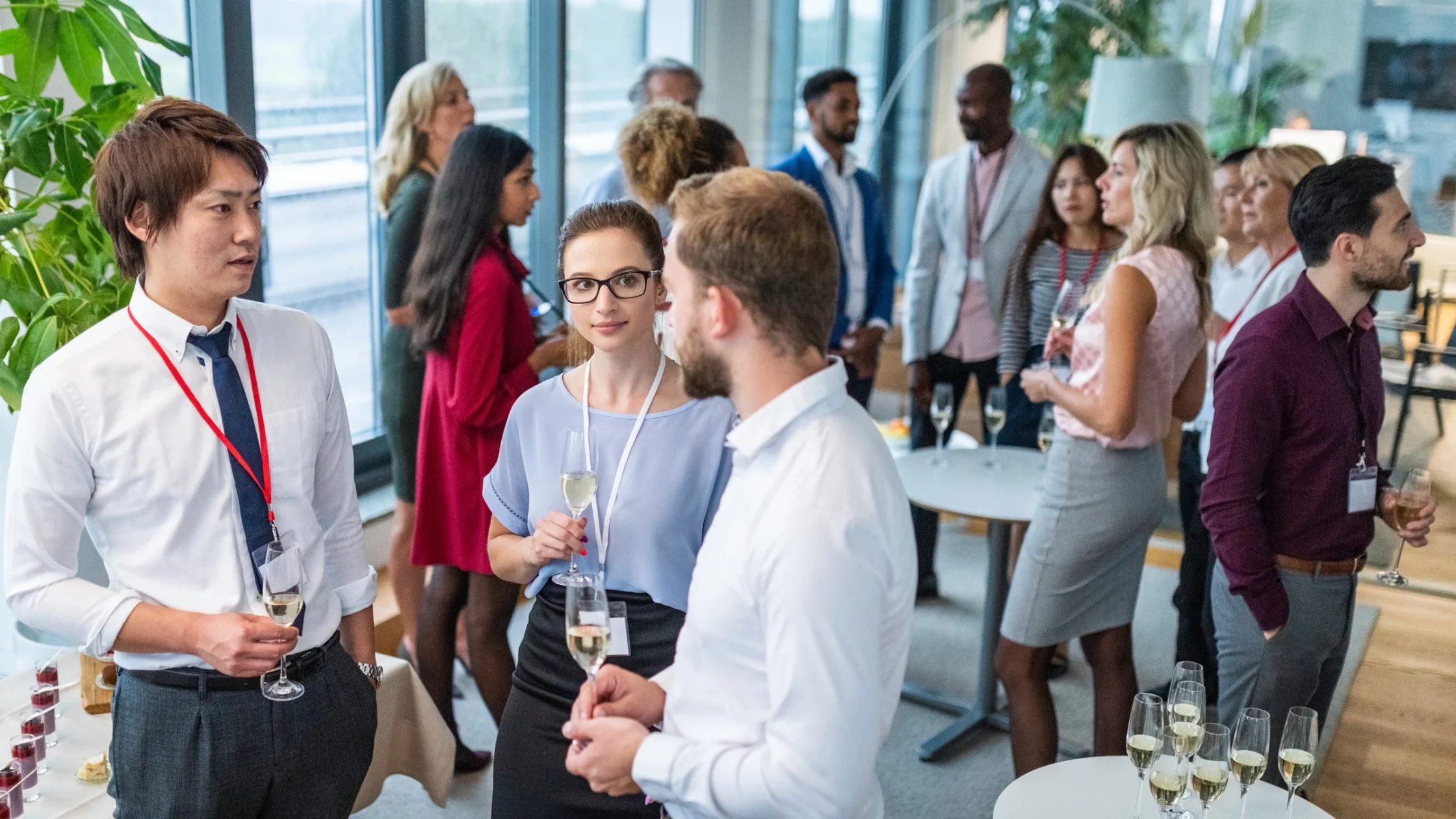 A diverse group of business professionals networking and holding drinks during an indoor cocktail reception at executive corporate retreats in Ghana.